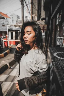 身穿灰色圆领衬衫、身穿夹克的女子站在黑色金属框架附近 身穿灰色圆领衬衫、身穿夹克的女子站在黑色金属框架附近