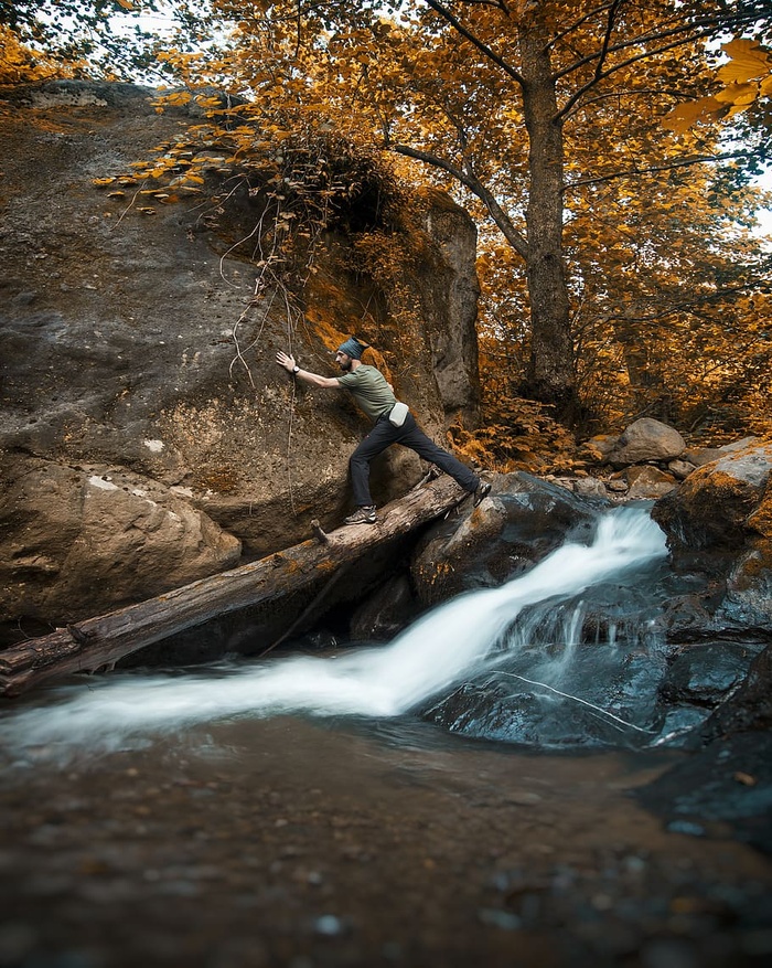 身穿绿色衬衫的男子踩在棕色圆木上