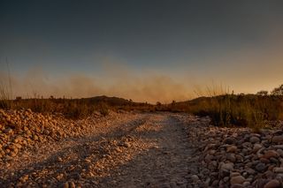 一条灰色的石头小路，位于棕色的草地和田野之间