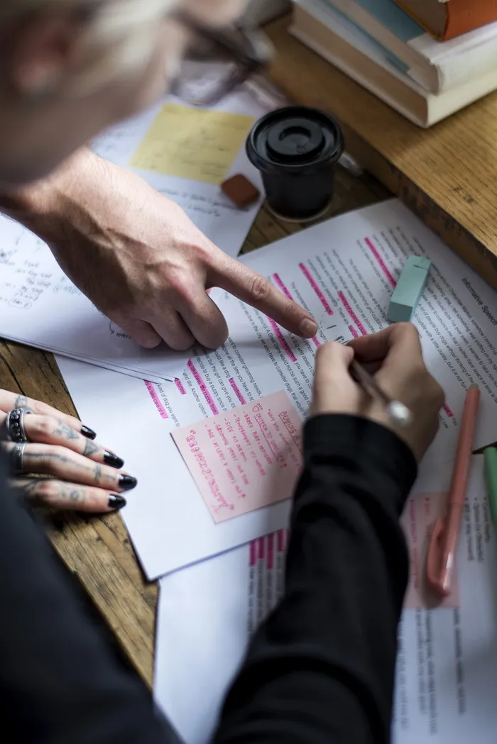 在米色木桌上的白色打印纸上写字的人