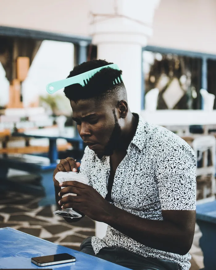 照片中的男子穿着白色纽扣领衬衫，头发上戴着梳子，正在吃冰淇淋