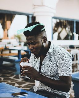 照片中的男子穿着白色纽扣领衬衫，头发上戴着梳子，正在吃冰淇淋