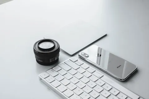 相机镜头和苹果键盘旁的银色iPhone X 相机镜头和苹果键盘旁的银色iPhone X
