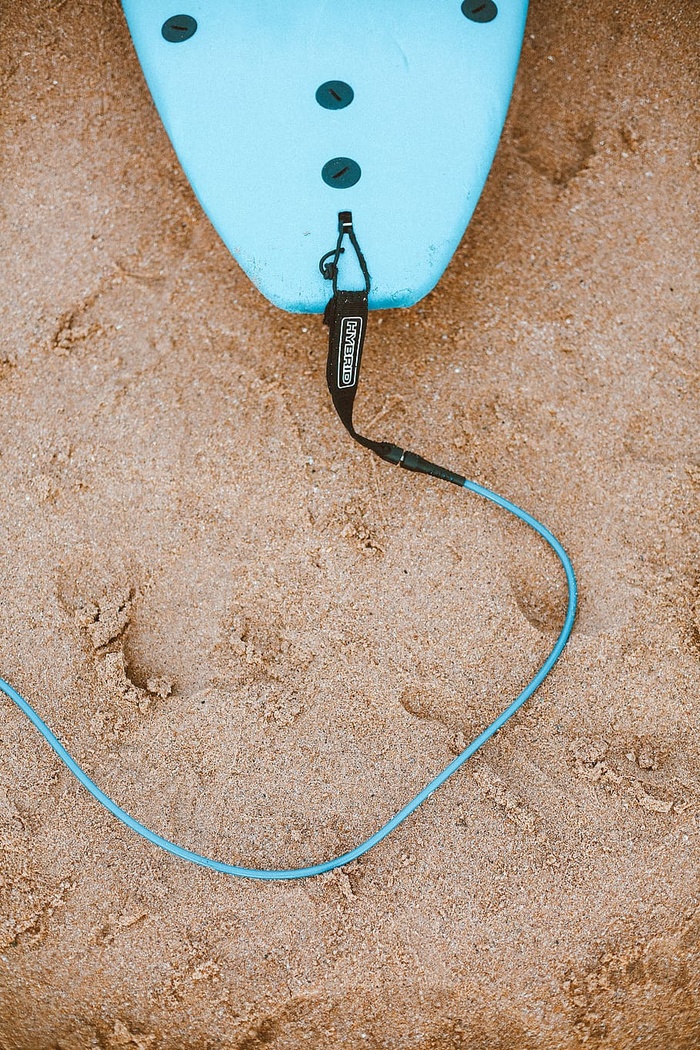 沙滩上带皮带的蓝色冲浪板照片