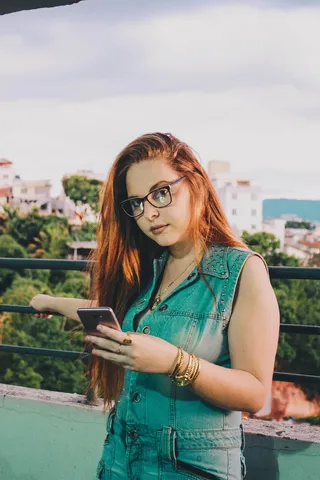 穿着蓝色牛仔无袖纽扣上衣的女士使用智能手机