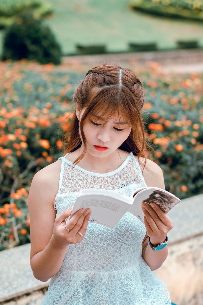 穿着白色无袖连衣裙看书的女人