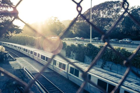 白天从链节围栏看火车在轨道上的景色