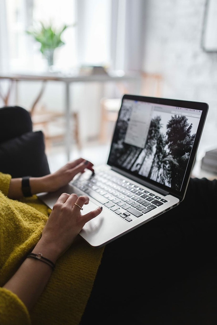 坐在沙发上用笔记本电脑工作的年轻女子