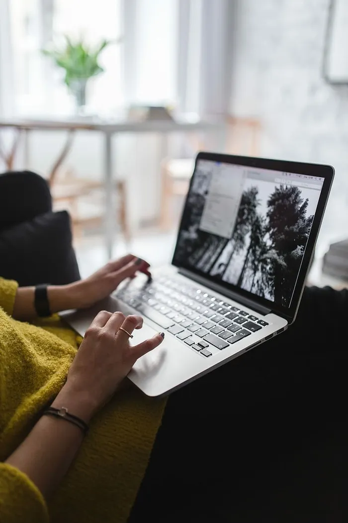 坐在沙发上用笔记本电脑工作的年轻女子