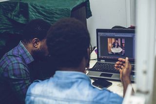 两名男子坐在笔记本电脑前的椅子上