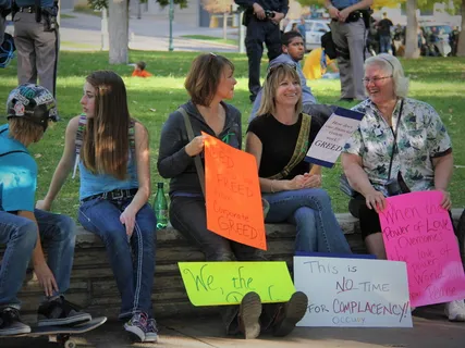 白天，人们坐在长凳上拿着签名纸板