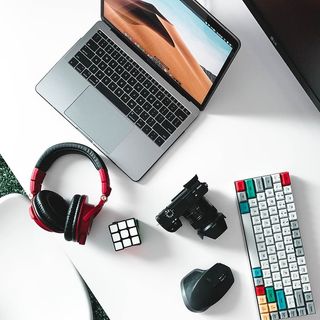 打开MacBook Pro，旁边是白色桌子上的红色和黑色无绳耳机