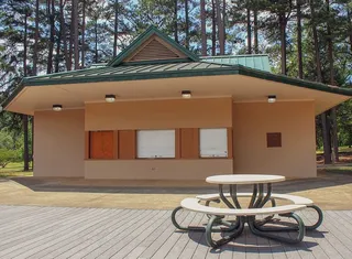 白天在树下的混凝土建筑前的野餐桌