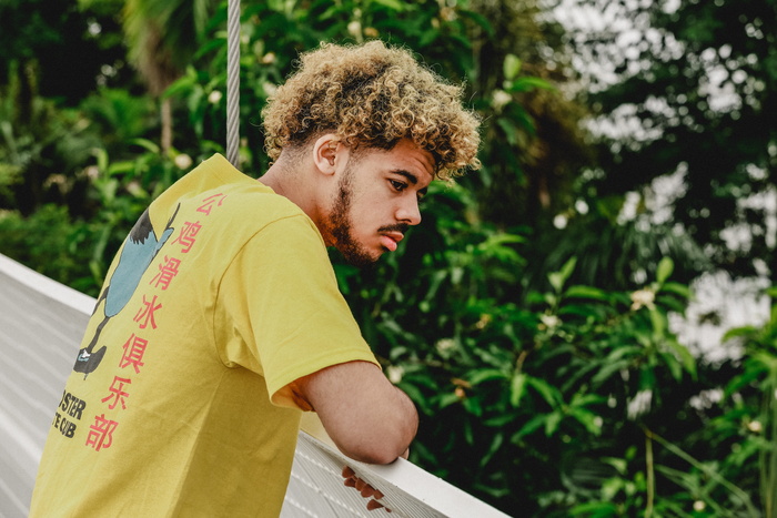 白天穿着黄色T恤站在树前的男人