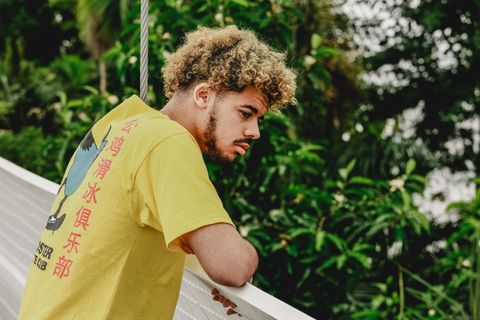 白天穿着黄色T恤站在树前的男人