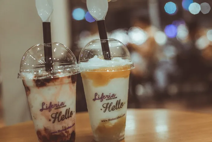 两杯Liferia Hello咖啡，放在棕色的木桌上