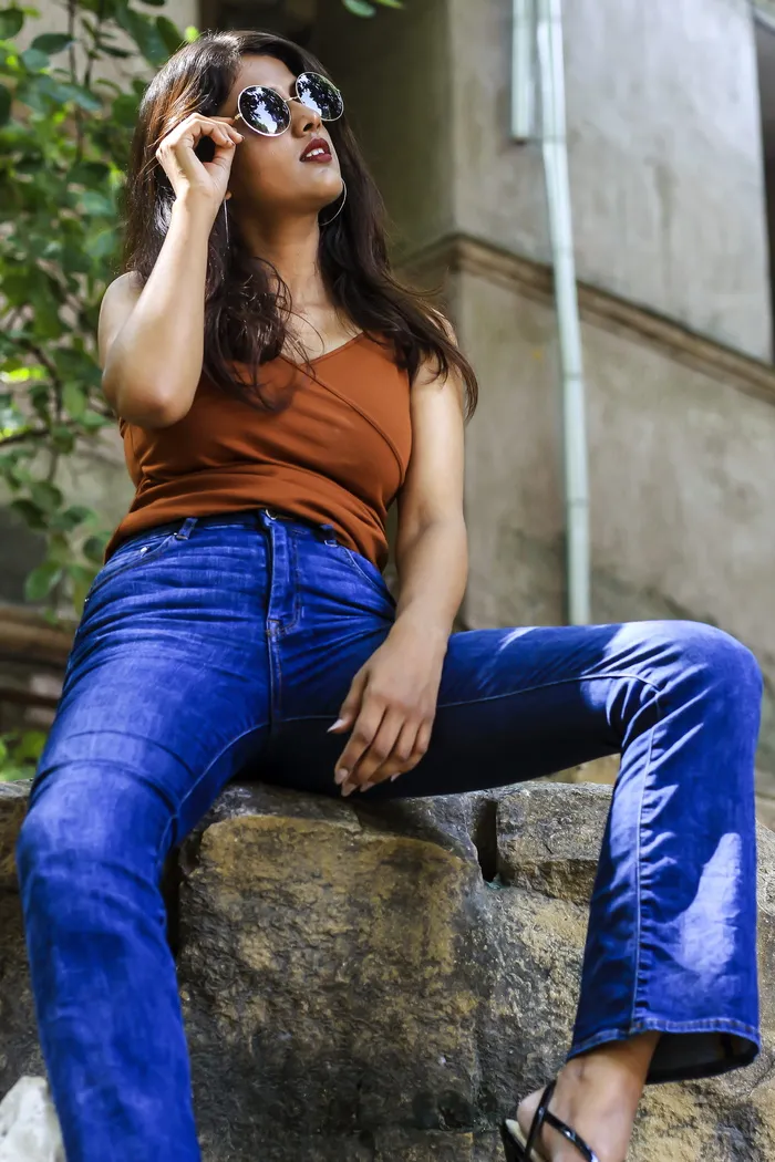 一名女子坐在岩石上，手里拿着她的旧太阳镜