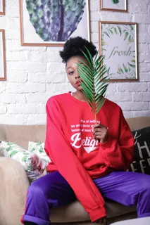 穿着红色毛衣和紫色裤子的坐着的女人 穿着红色毛衣和紫色裤子的坐着的女人