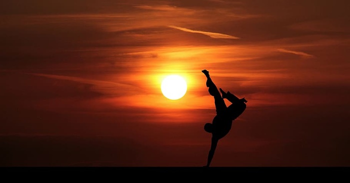 武术家在橙色夕阳下倒立的剪影。