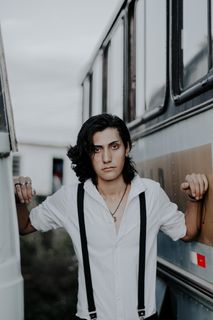 身穿白色衬衫的男子在两辆公交车之间摆姿势的照片