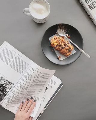 面包放在白色陶瓷杯旁的黑色圆形盘子上