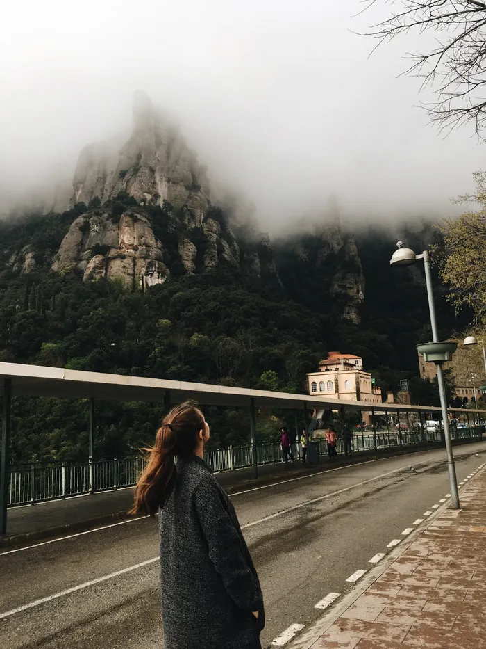 一名身穿黑色夹克的女子站在山旁的照片