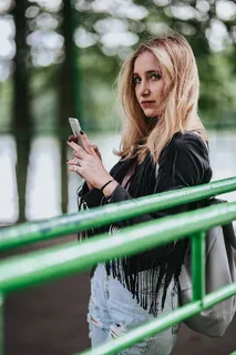 穿着黑色夹克和绿色扶手撕破牛仔裤的金发女人 穿着黑色夹克和绿色扶手撕破牛仔裤的金发女人