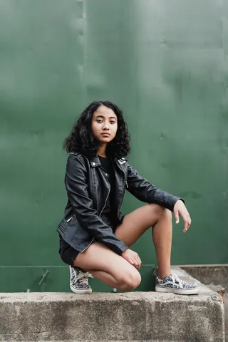 白天坐着穿着黑色拉链夹克和短裤的女性