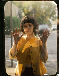 照片中，一名女子举着双手，穿着短上衣