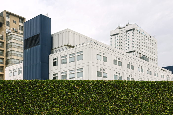 灌木墙后的白色和蓝色高层建筑