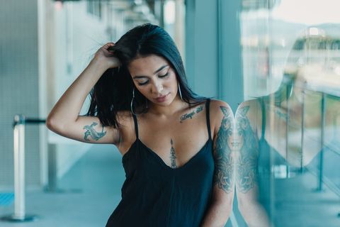 穿着背心站在玻璃墙旁边的女人