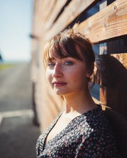 一名女子站在棕色木墙前的特写照片