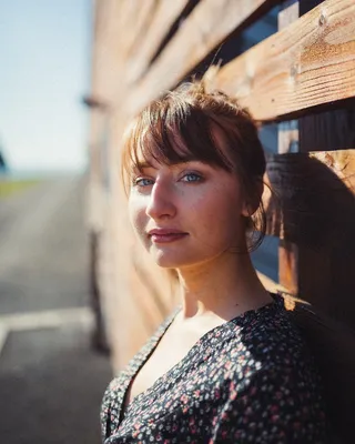 一名女子站在棕色木墙前的特写照片