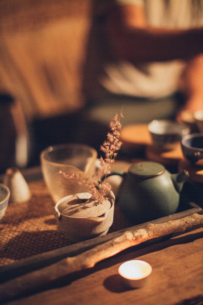 木棒和陶瓷茶壶旁边的点燃的茶灯