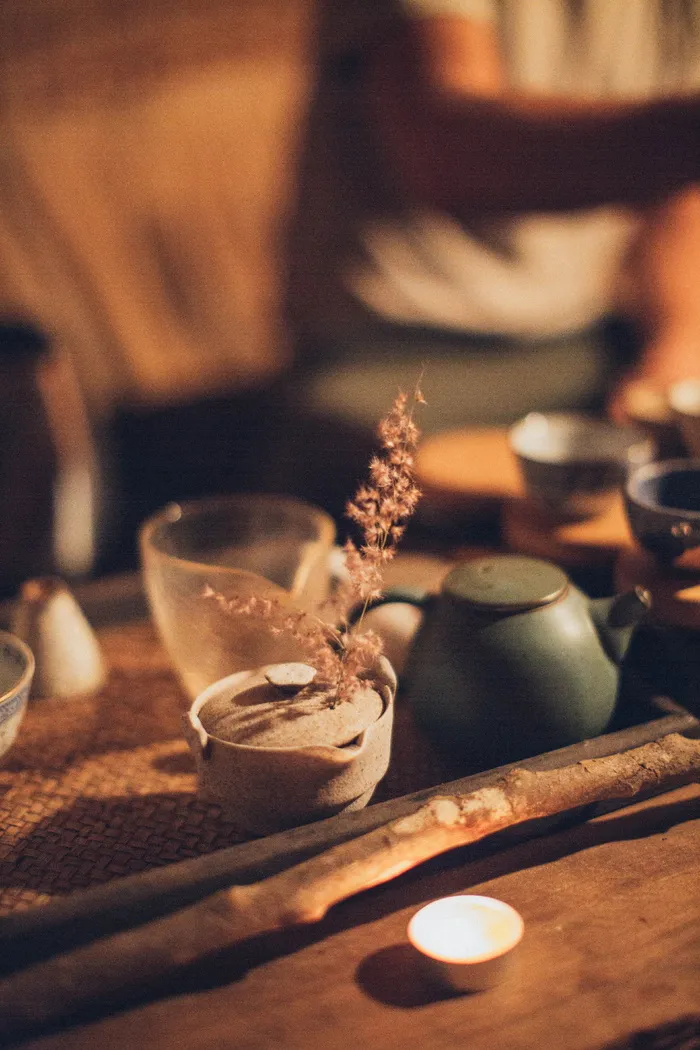 木棒和陶瓷茶壶旁边的点燃的茶灯