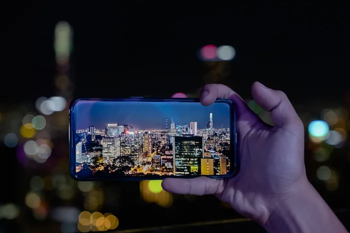 使用智能手机拍摄城市照明建筑的人