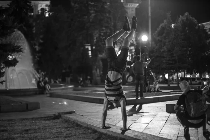 一个男人在公园里做手站的灰度照片