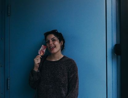 一名女子拿着冰激凌在棍子上吐舌头