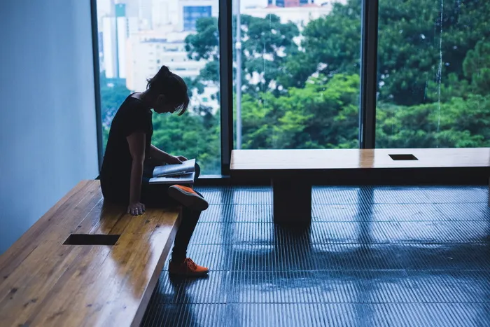一名妇女坐在玻璃窗旁的棕色木椅上