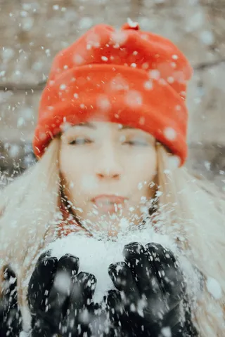 手持雪球、戴橙色针织帽的女子