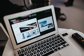 白色笔记本电脑放在一张带遥控器的桌子上