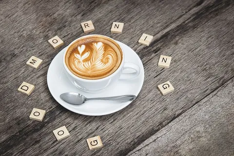 银茶匙旁的白色陶瓷咖啡茶杯 银茶匙旁的白色陶瓷咖啡茶杯