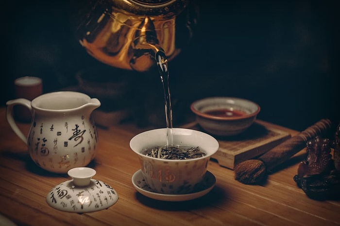 把热水倒在茶杯上的金壶