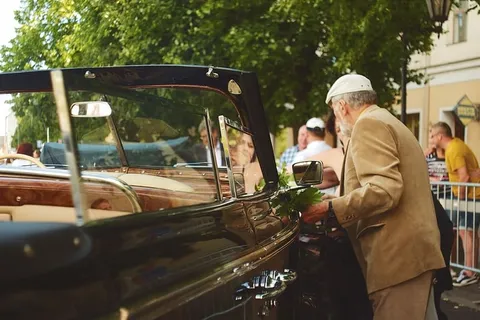 身穿棕色西装的男子站在汽车旁边