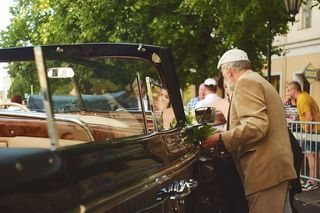 身穿棕色西装的男子站在汽车旁边