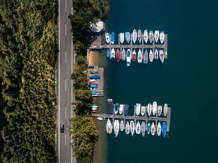 道路旁棕色木质码头的航拍照片，白天码头上停放着各色船只