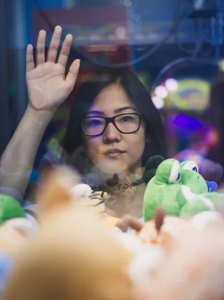 一个女人在看装满毛绒玩具的起重机