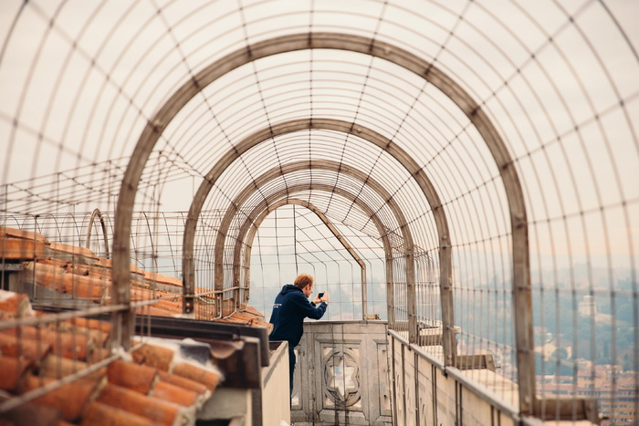 一名年轻的白人男子在屋顶走道上用相机拍照