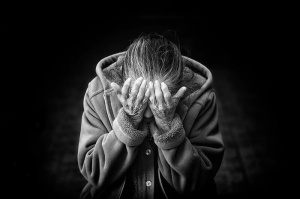身穿纽扣连帽夹克的人把手放在眼睛里的灰度照片