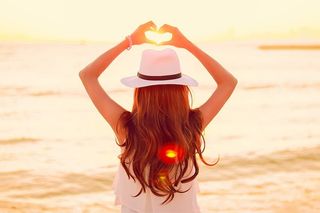 戴着白色软呢帽、身穿白色无袖上衣的女子站在水体附近